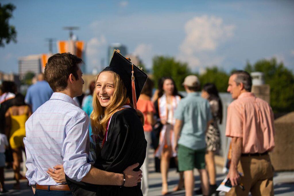 A student in cap and gown smiles as she leaves graduation