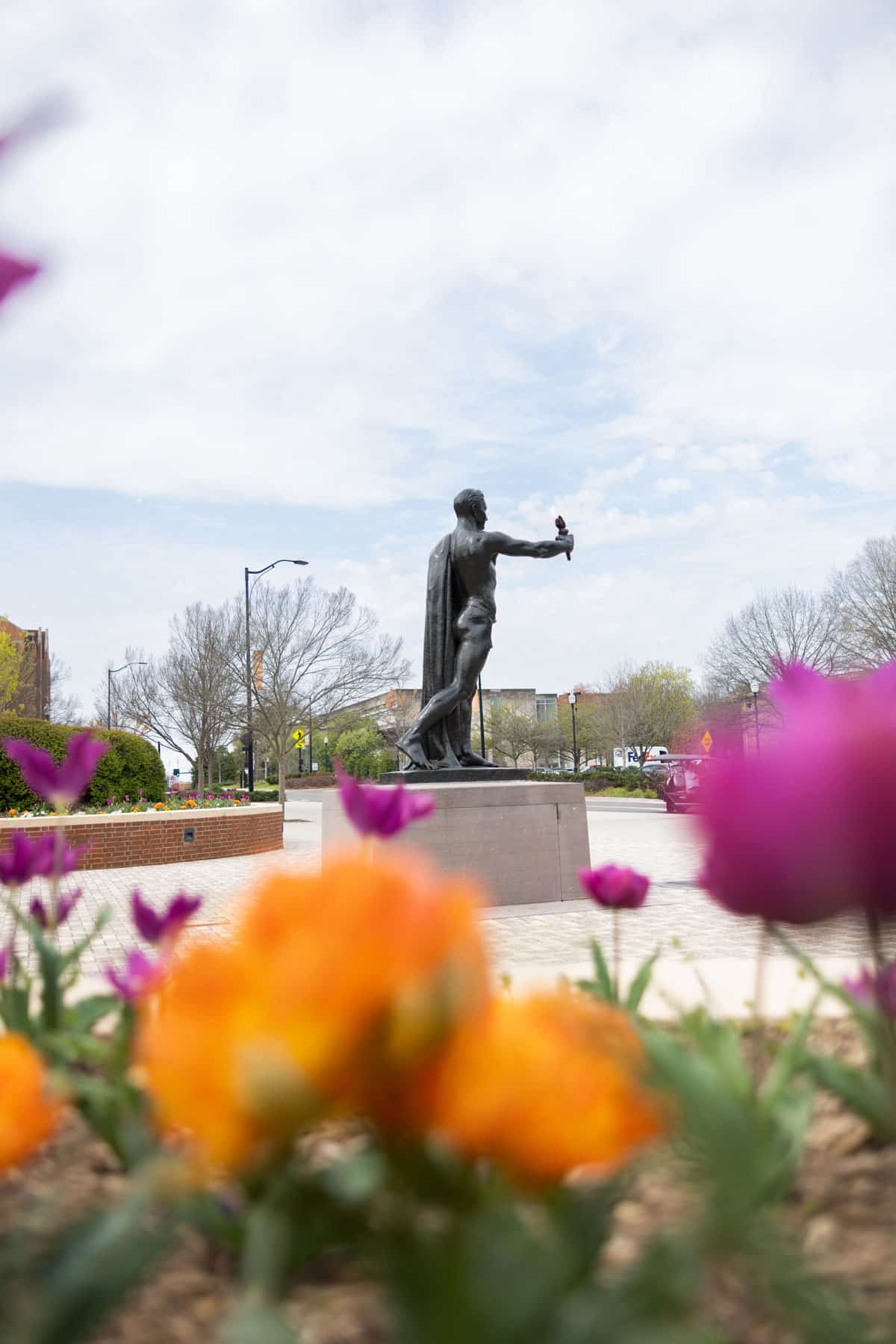 Torchbearer from a distance with orange and pink tulips in the foreground.