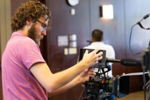 A student adjusts a camera during a filming session
