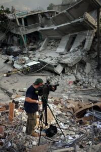 Jerry Simonson facing video equipment towards rubble in Haiti after a natural disaster.