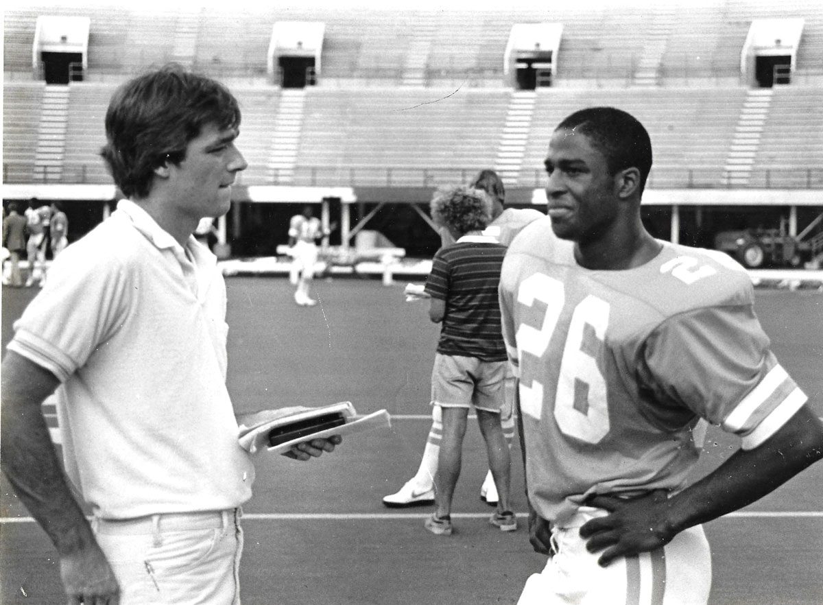 In this black and white photo, Daily Beacon editor Jeff Copeskey interviews a football player on the field.