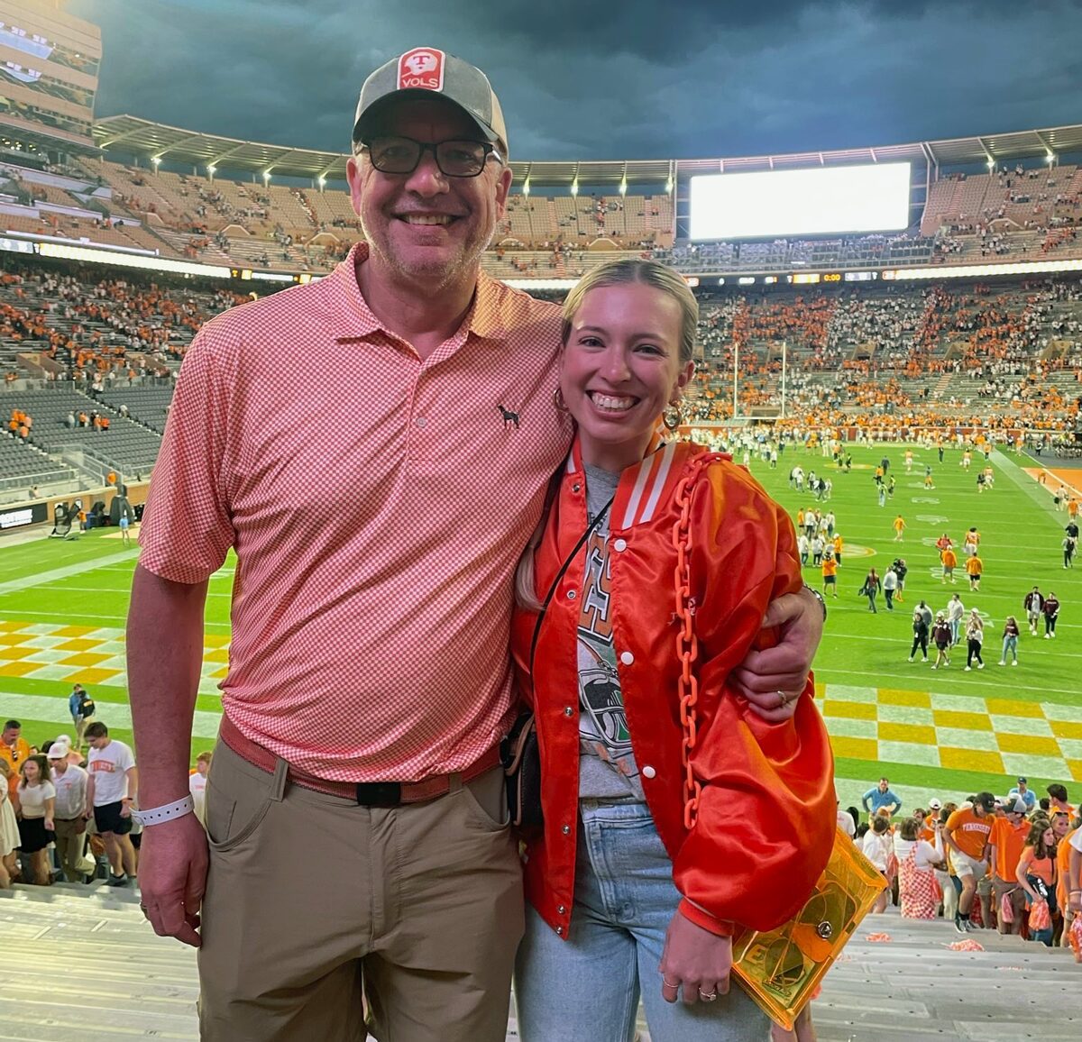 Eric Jackson and his daughter Kaitlin Shayotovich side hug in Neyland Stadium with the field and seats in the background behind them.