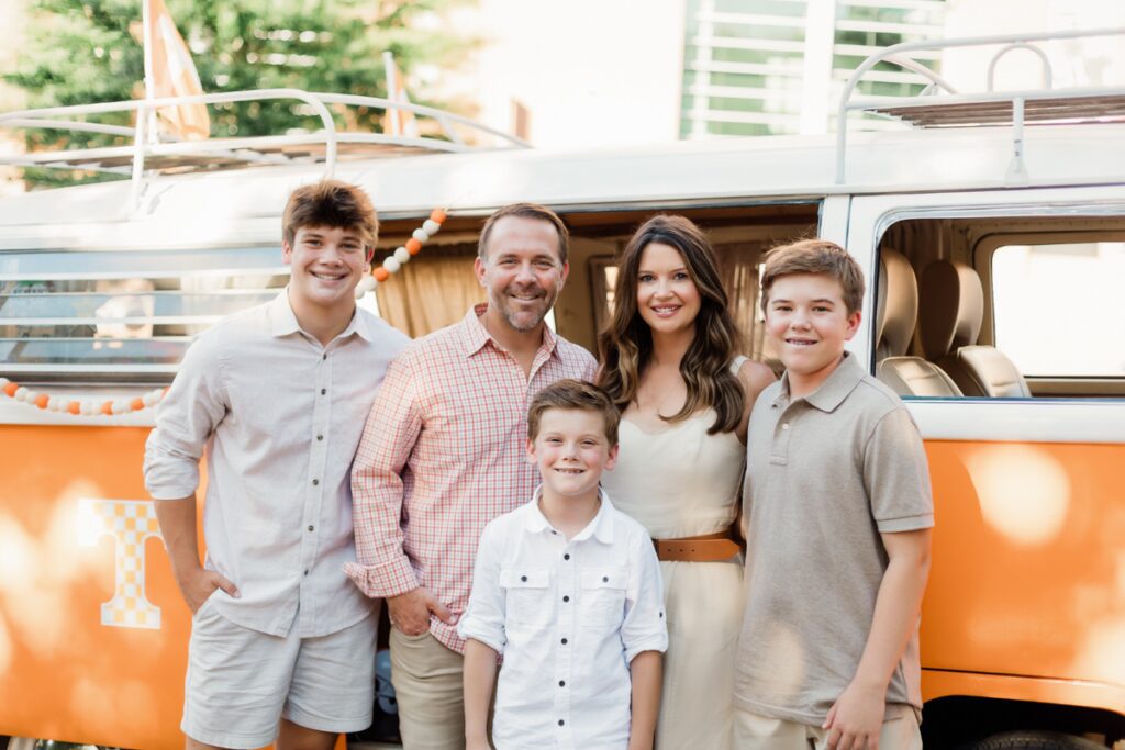 The Haag family stands in front of an orange and white Volkswagen minivan 