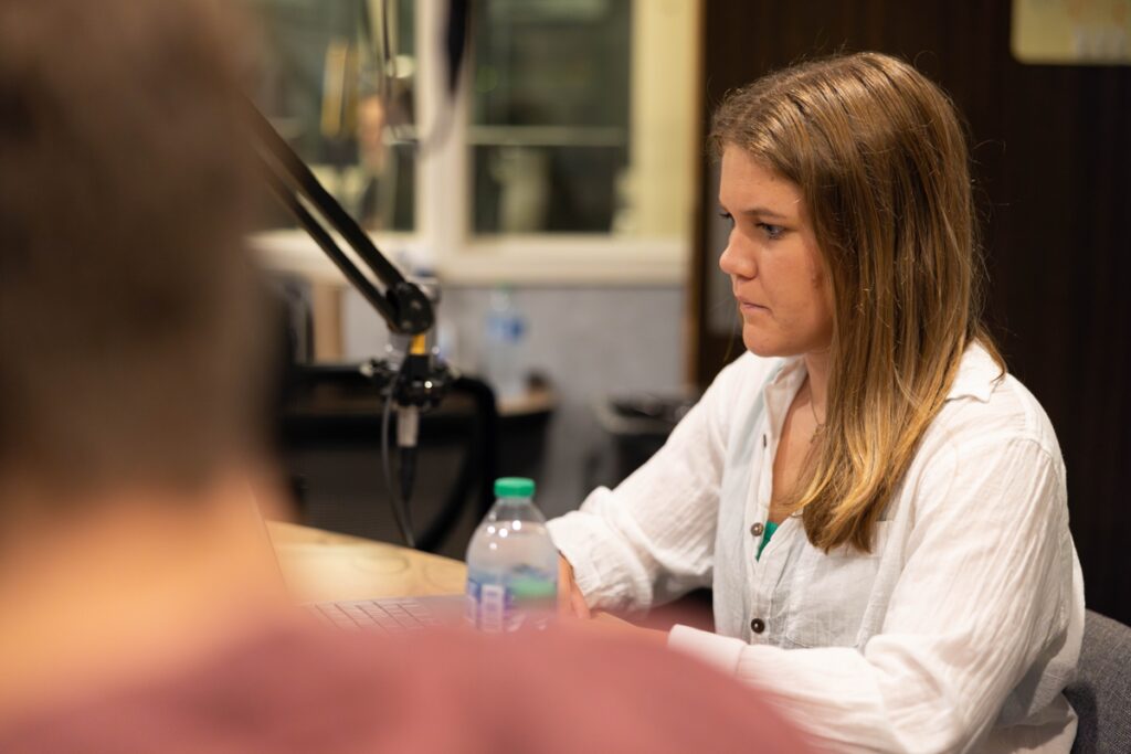 Student Mary Beth Mahne sits in front of a microphone at a WUOT desk.