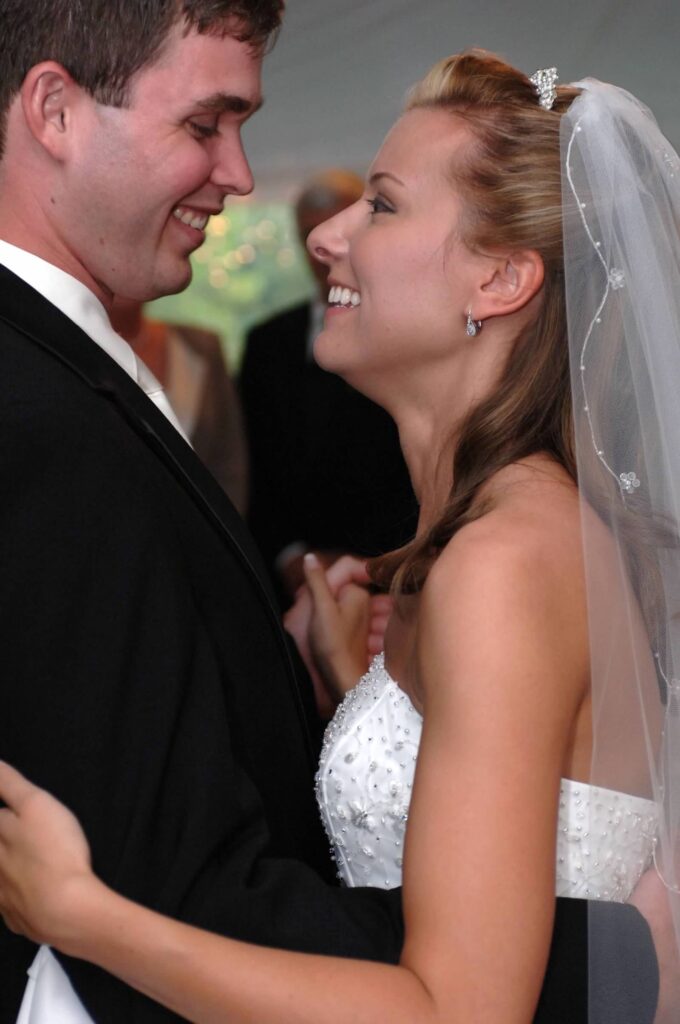 Lee and Erin Freeman dancing at their wedding; he's in a black suit and she's wearing a white wedding dress and veil, looking up at him smiling while he smiles back at her.