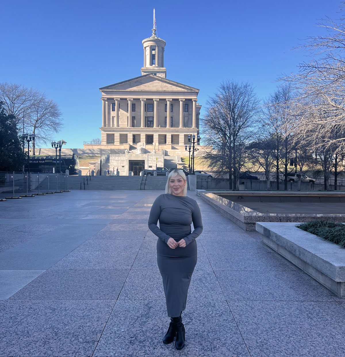 Jennifer Azrate stands on a paved walkway with the Tennessee capitol building in the background behind her.
