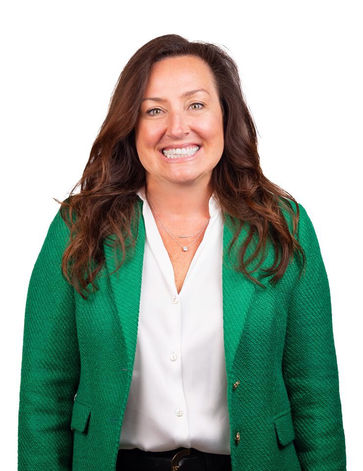 A headshot of Courtney Childers wearing a white button up shirt and a kelly green suit jacket in front of a white background.