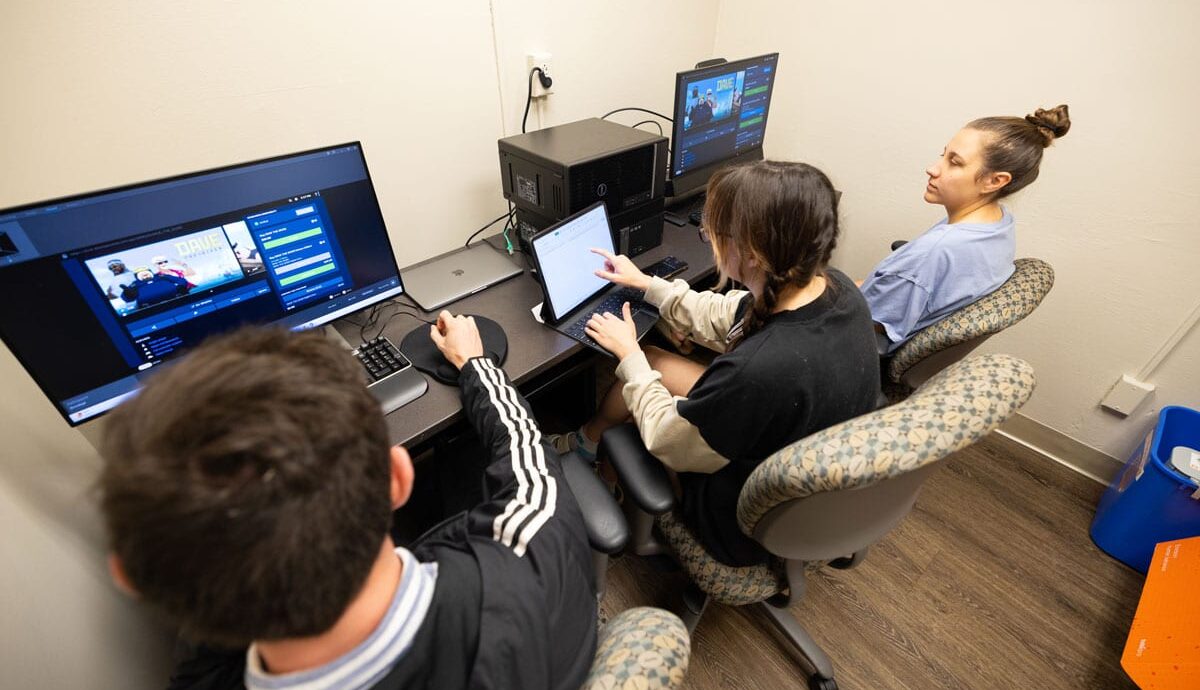 Two students sit with User Experience Lab director Logan Montuori at computers in the lab while they conduct testing.