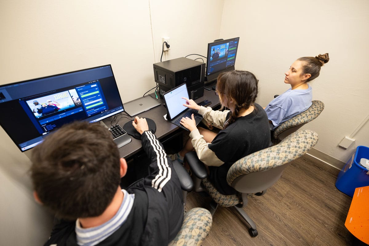 Two students sit with User Experience Lab director Logan Montuori at computers in the lab while they conduct testing.