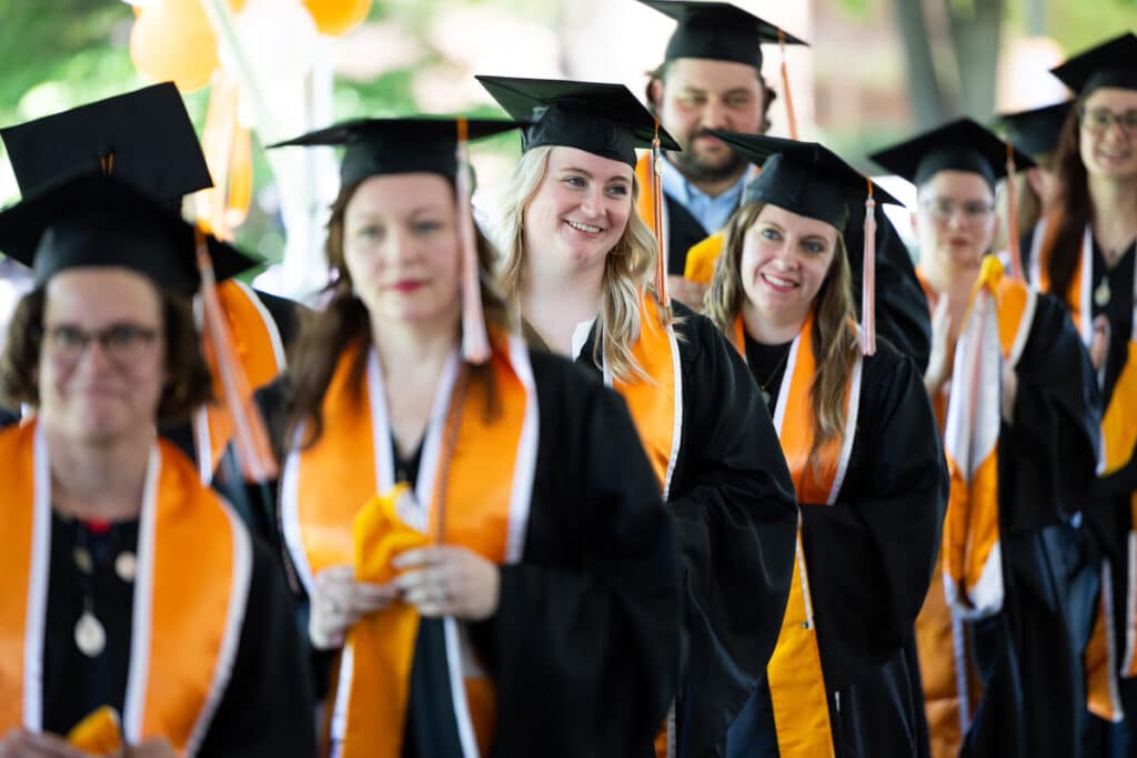 Graduate students in the School of Information Sciences line up to receive their diploma at their hooding ceremony.