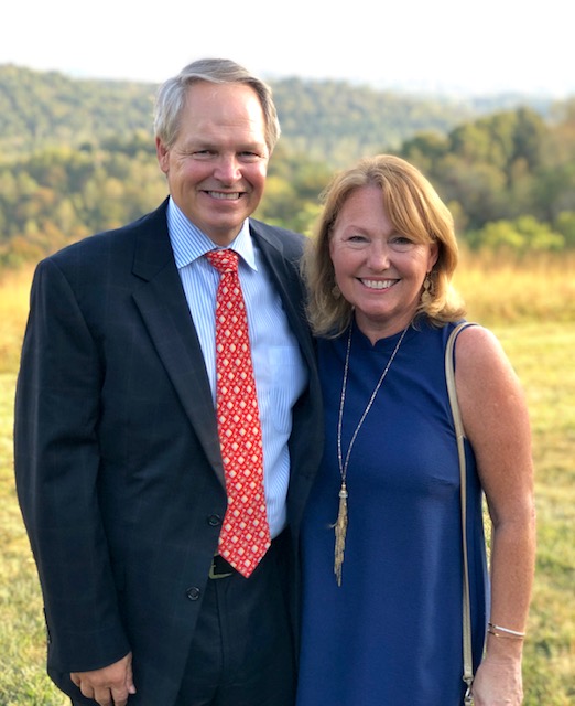 Alan and Wendy Wilson pose together with green hills behind them.