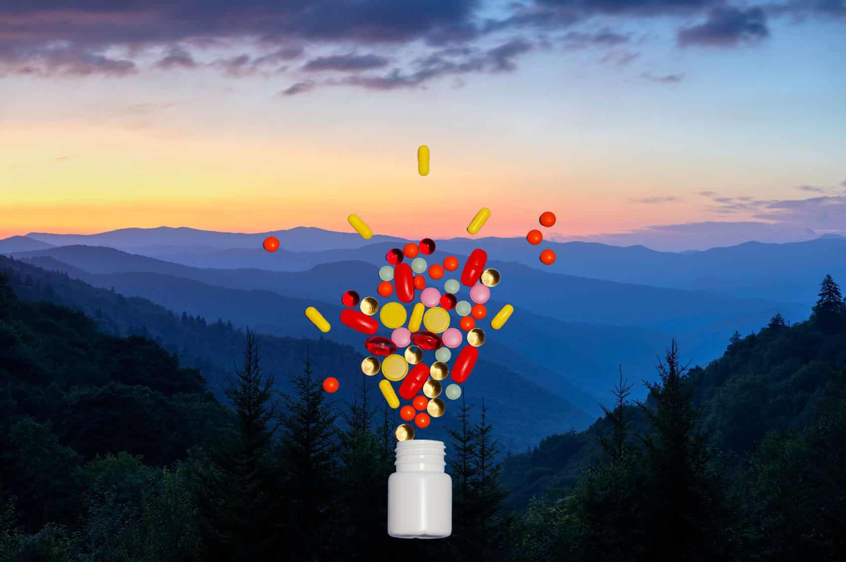 A white medicine bottle with pills spilling out of it in a V shape is superimposed over an image of the Smokey Mountains at sunset.