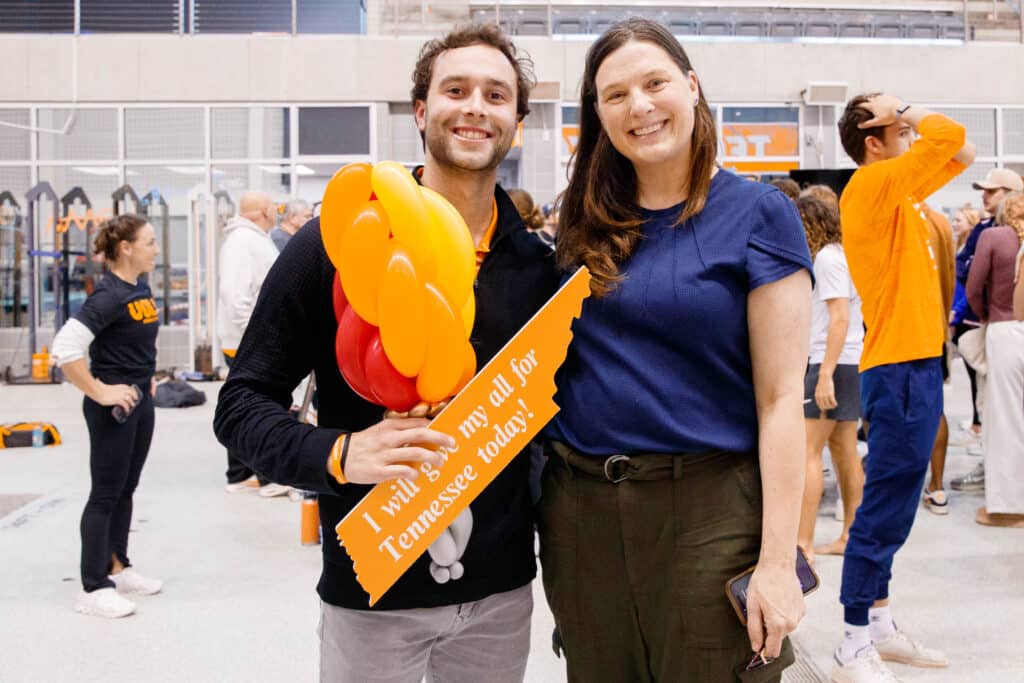 A photo of School of Journalism and Media Griffin Hadley and Professor Erin Whiteside smiling together as they celebrate Hadley being named a UT Torchbearer following the surprise announcement at the Allan Jones Intercollegiate Aquatic Center.