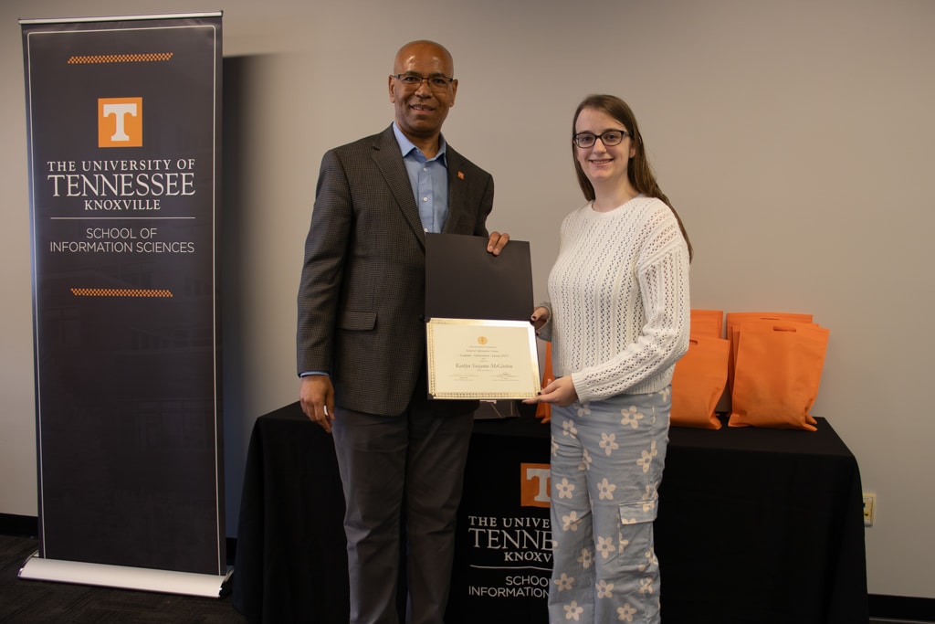 Kaitlyn Suzanne McGlothin, on the right, accepts the Academic Achievement Award from SIS Director Abebe Rorissa.