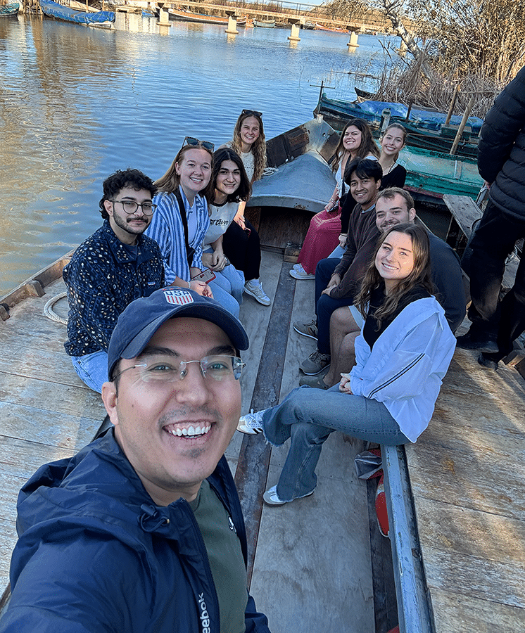 A photo School of Journalism and Media Professor Mustafa Oz grabbing a selfie with students on a river boat in Spain this past spring as part of the 2026 CCI Global Communication Scholars Semester program.