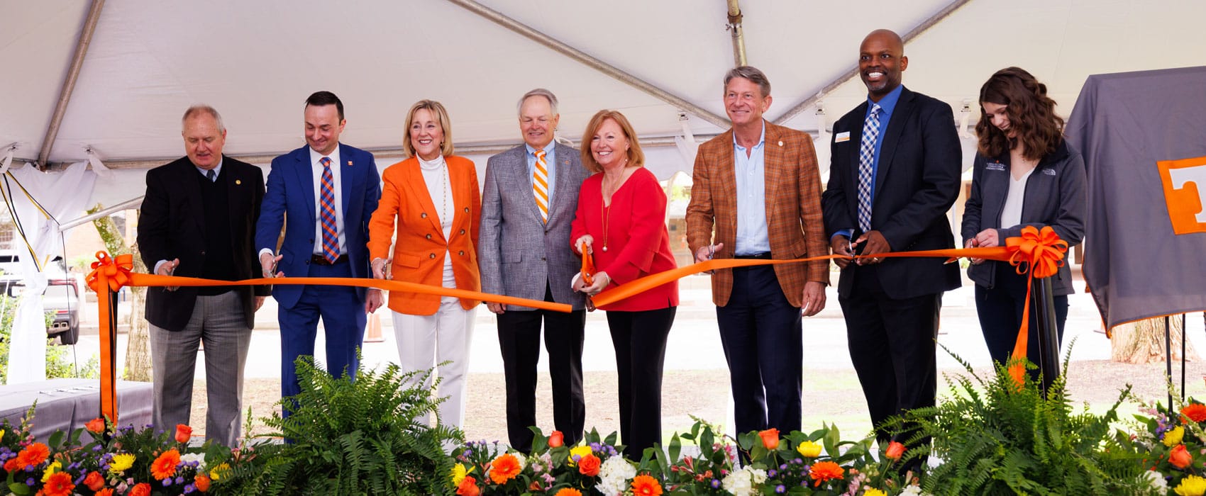 Alan and Wendy Wilson use large scissors to cut an orange ribbon to celebrate their new academy. They are joined by several U-T and C-C-I administrators and a student.