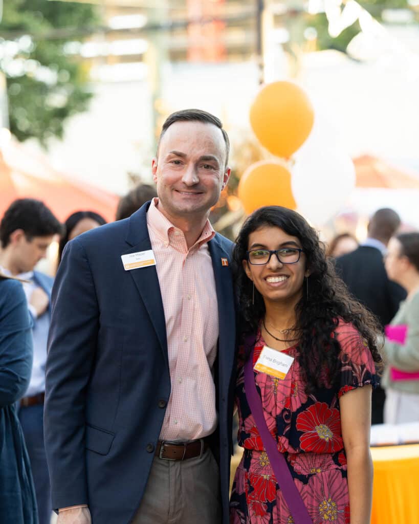 CCI Dean Joseph Mazer in a blue jacket and a checkered orange and white shirt with senior Sana Boghani, who is wearing a floral blouse and pants during the college's alumni reception as part of the 2025 industry networking trip to Nashville, Tennessee.